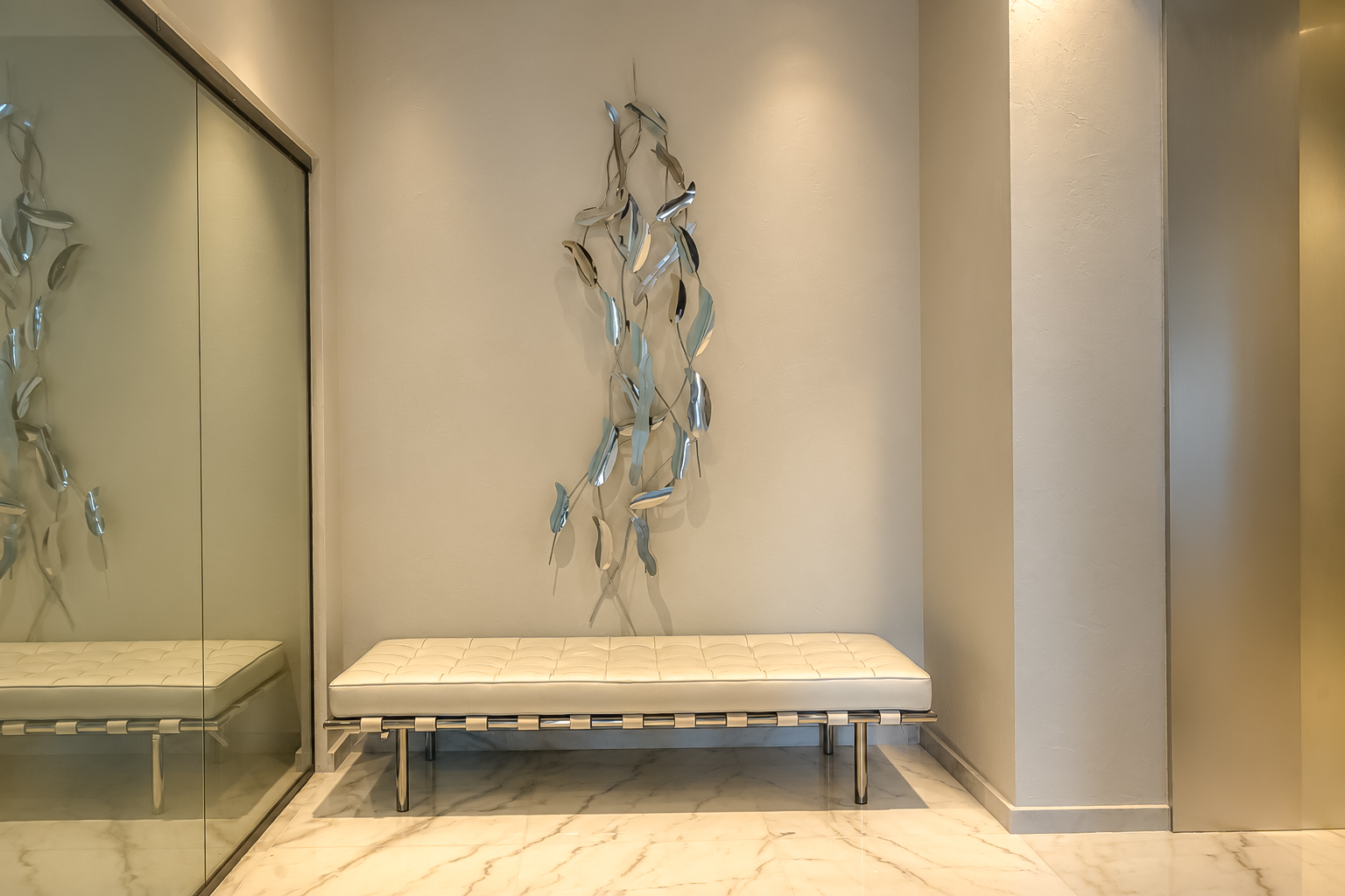 White daybed and chrome leaf sculpture in the marble hall