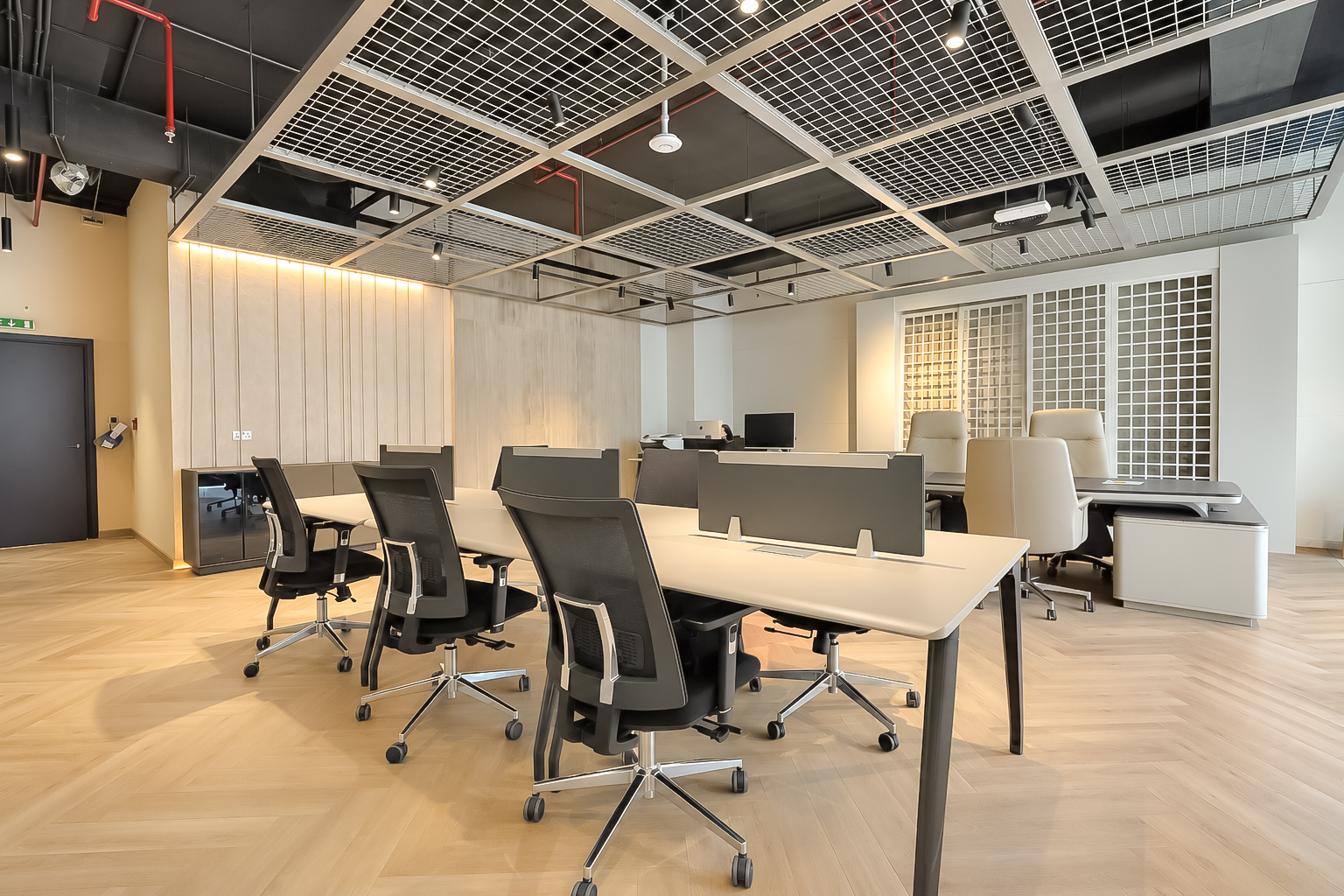 Open-plan desks with mesh chairs on herringbone oak